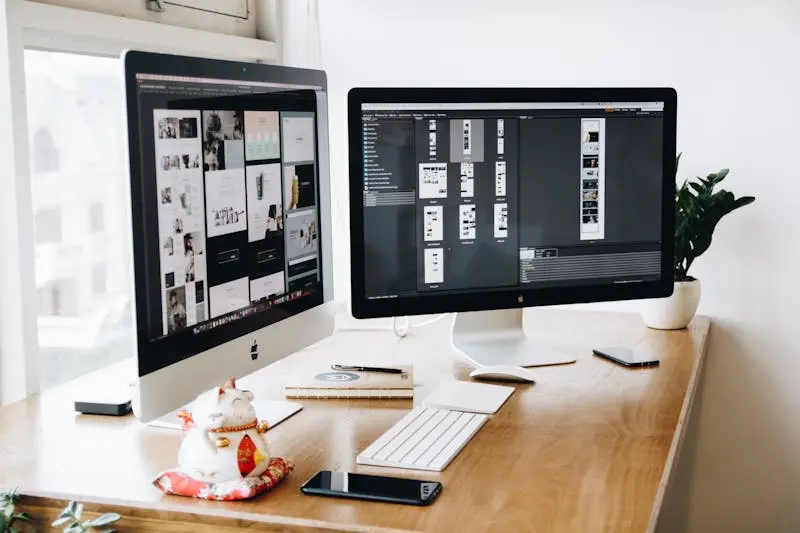 Two mac computer with design projects and mobile on the table