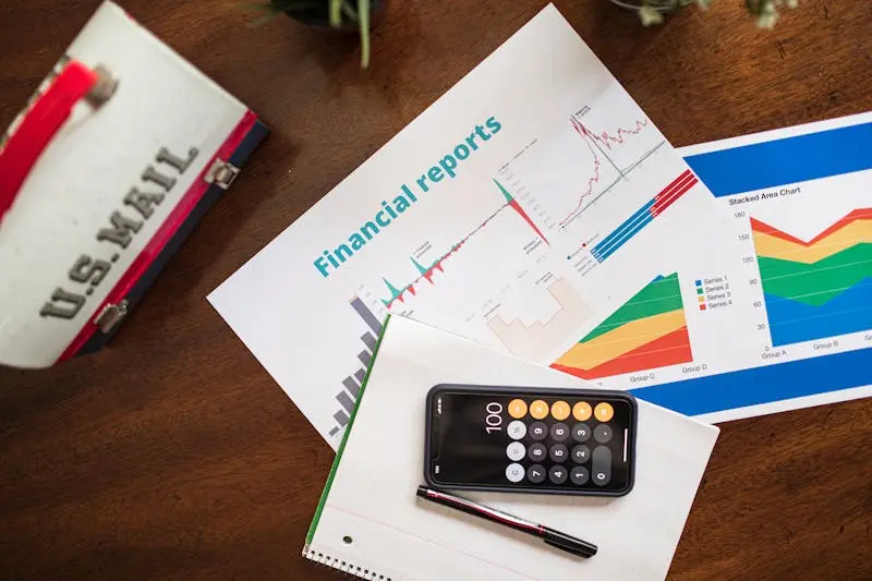 calculator on mobile phone with financial reports on table.