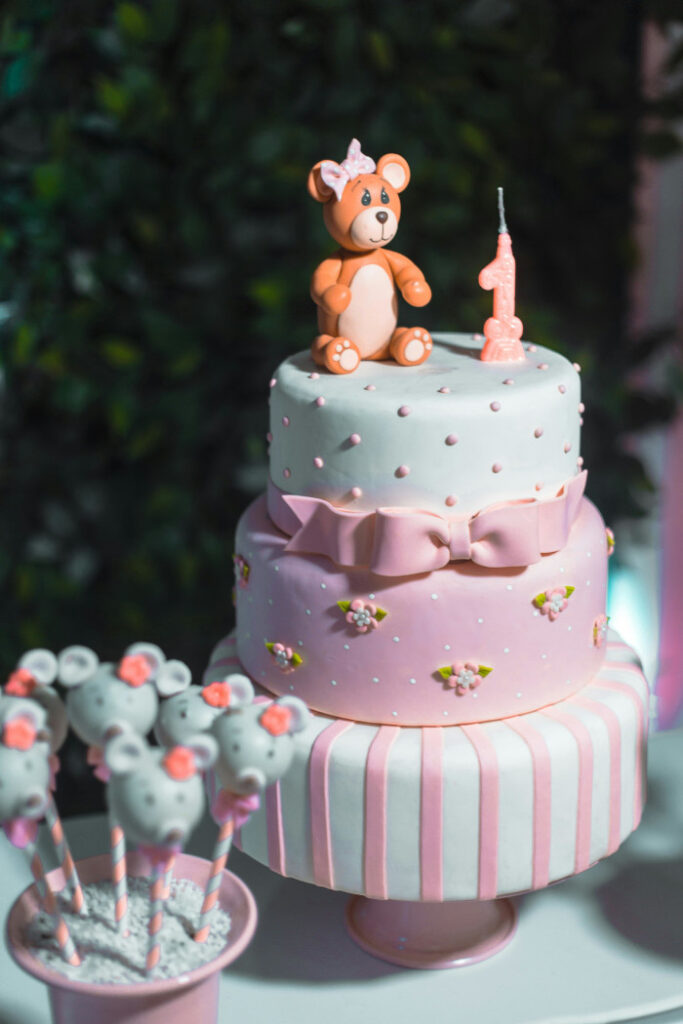 pink and white birthday cake with small teddy bear