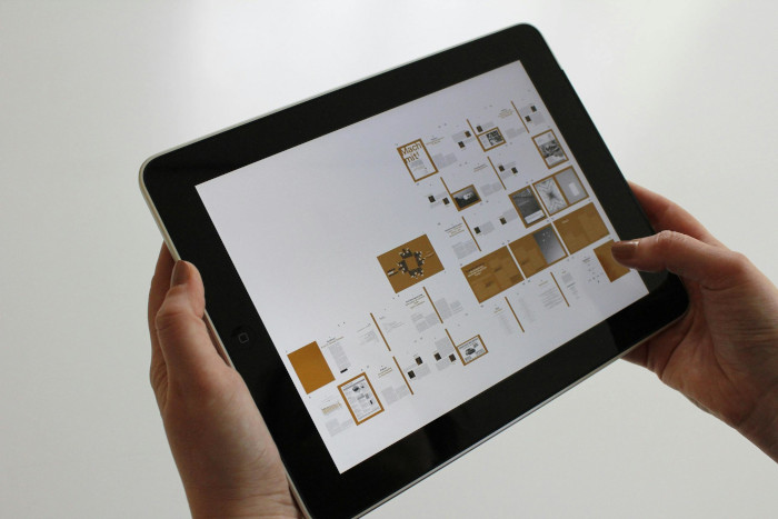 Person holding a tablet displaying a digital layout design