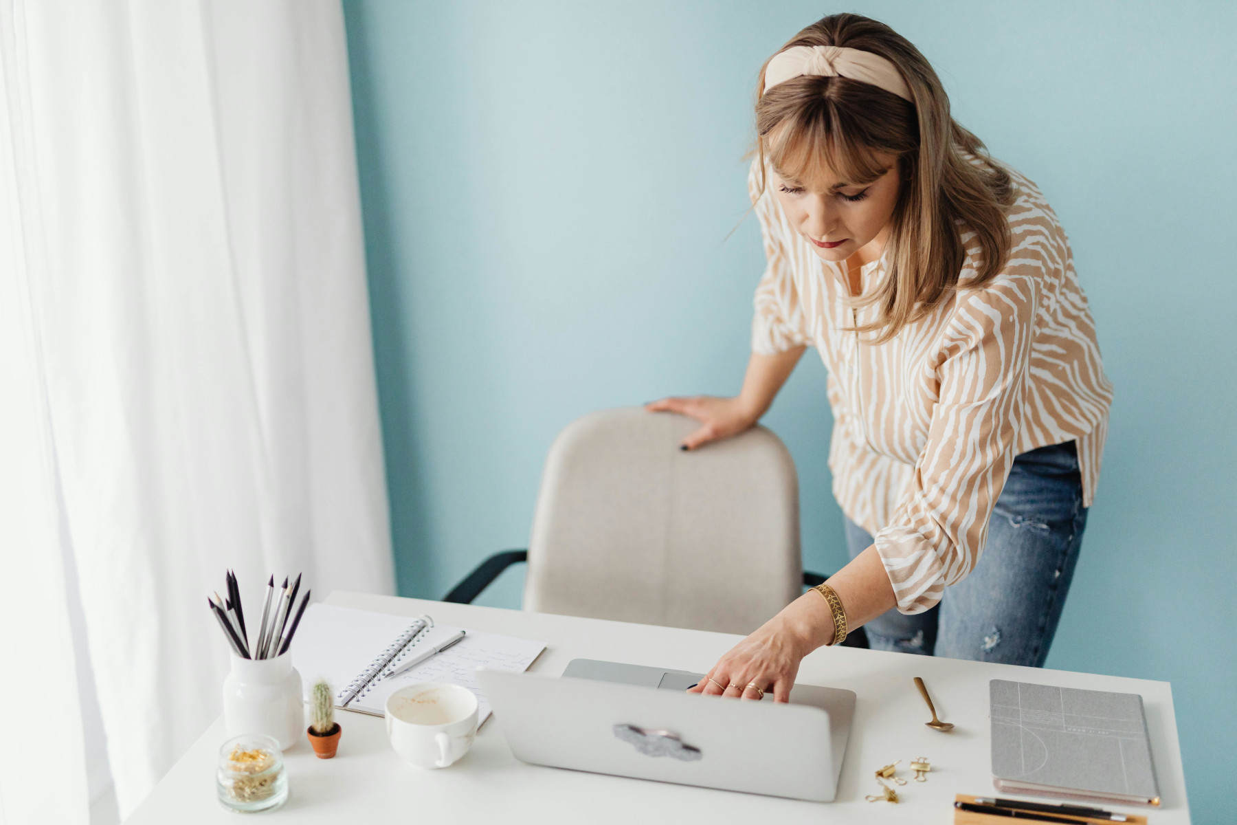 A Woman Standing at the Table Using a Laptop